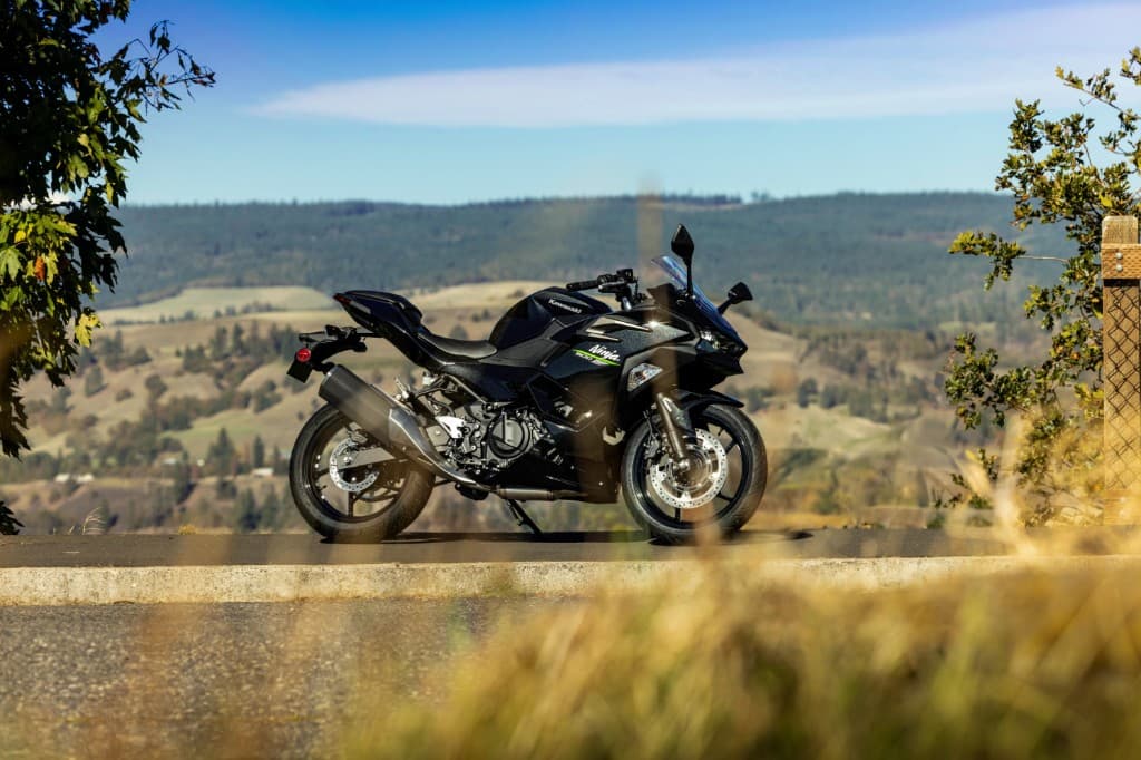 Black Kawasaki Ninja sport motorcycle parked at a scenic roadside lookout overlooking rolling hills