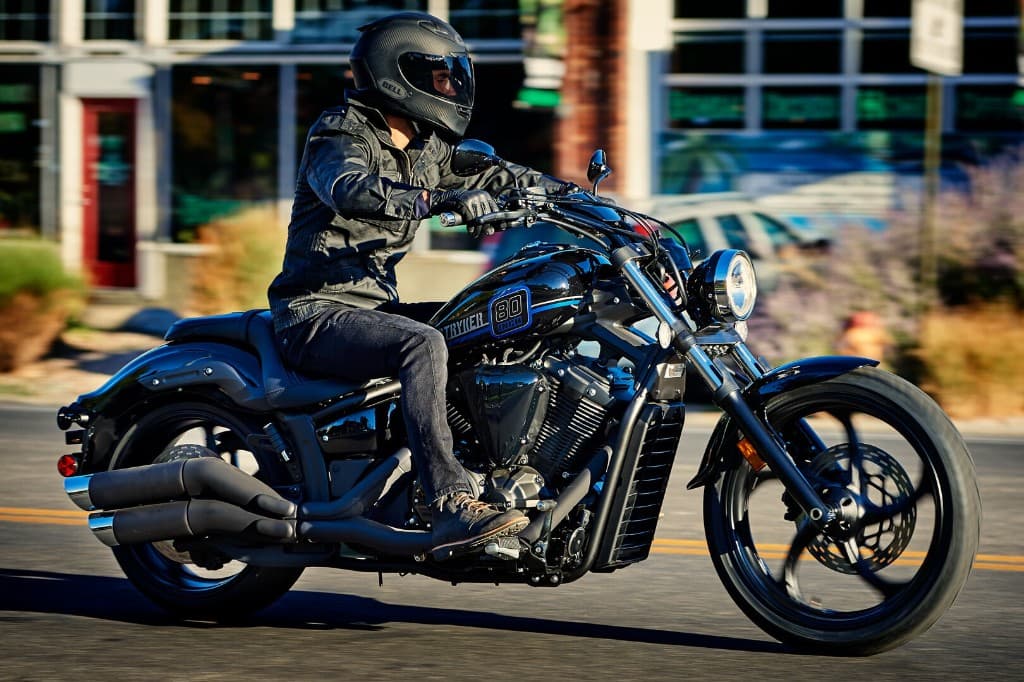 Motorcyclist in full protective gear riding a black cruiser motorcycle on a city street