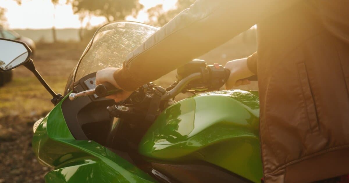 Rider in a brown leather jacket on a green motorcycle at sunset, representing Australian motorcycle ownership and riding culture